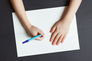 Children's hand with a pen on a white paper