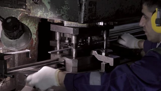 Machine operator works in a factory and stamps metal products