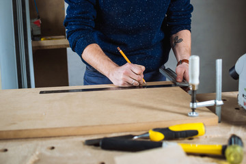 Young man working as carpenter and measuring board
