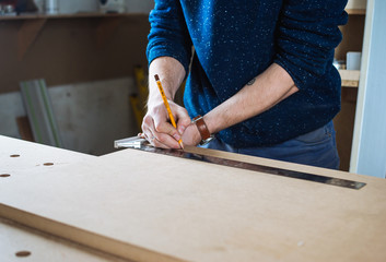 Young man working as carpenter and measuring board