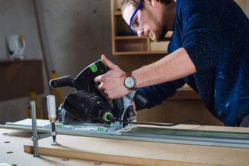 Young man working as carpenter and measuring board