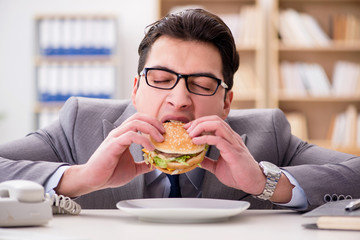 Hungry funny businessman eating junk food sandwich