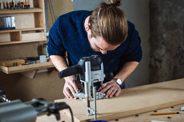 Young man working as carpenter and cutting board