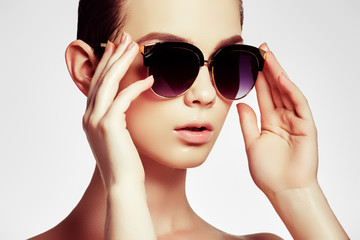 Fashion sunglasses. Sexy woman in swimsuit with golden sunglasses and natural makeup. Glamour shot...