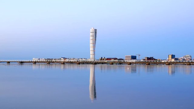 Turning Torso skyscraper building reflected in calm water surface. Modern architecture apartment tower block by the sea