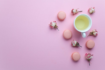 Fototapeta na wymiar Green tea and pastel french macarons cakes on pink background. Dessert in a garden. Flat lay. Free text space.