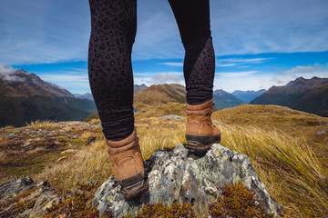 Detail of woman's legs in trekking shoes with mountain range background