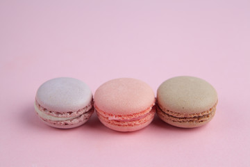 French colorful macarons on a pink background