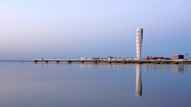 Modern architecture Turning Torso skyscraper building reflected in calm water surface. Apartment tower block by the sea, Malmo, Sweden