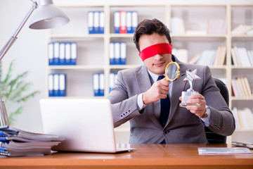 Blindfold businessman sitting at desk in office