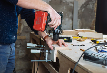 Young man piercing a hole through a wooden plank