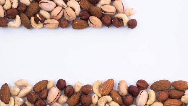 At the top and bottom of the shot moving strips of assorted nuts. Frame made of different types of nuts. Stop motion