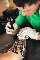 Master tattoo artist in gloves makes tattoo on hand men