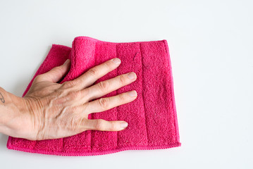 Close up high angle view of woman's hand holding pink microfibre cleaning cloth (selective focus)