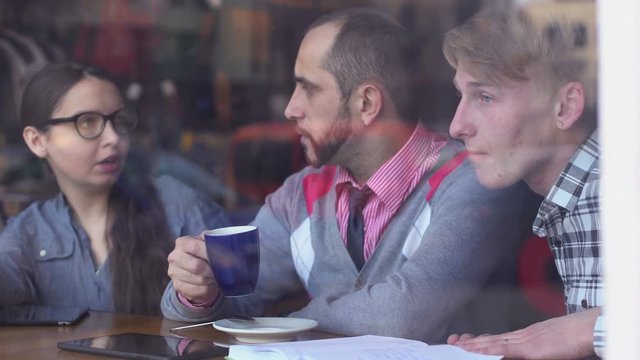Three young, creative people met in a cafe and discussing project
