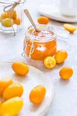 kumquat on plate and jam in jar at gray background