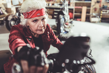 Serene grandmother driving motorcycle from garage