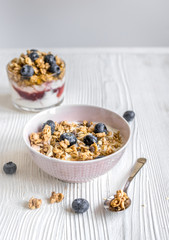 Homemade fitness granola with yoghurt and berries on white kitchen background