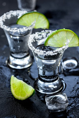 Alcohol party with tequila, ice and salt on black background