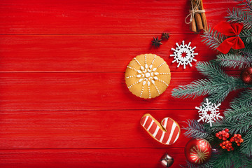 Composition of tasty gingerbread cookies and Christmas decor on red wooden background