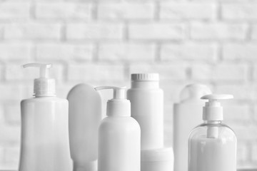 Plastic bottles of baby cosmetic products on white brick wall background