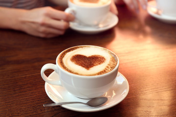 Cup of hot tasty coffee on wooden table, close up view