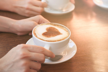 Female hands with cup of hot tasty coffee in cafe, close up view