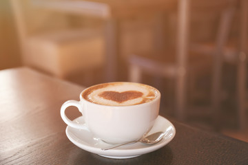 Cup with hot tasty coffee on wooden table in cafe, close up view