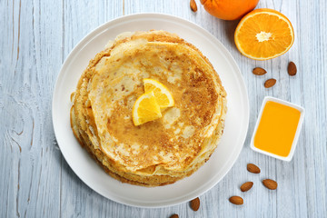 Stack of delicious pancakes with orange on wooden table