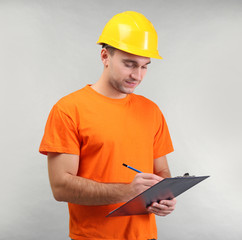 Handsome warehouse worker with clipboard on light background