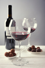 Chocolate truffles and glasses with red wine on white wooden table