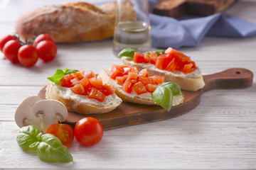 Delicious bruschetta with chopped tomatoes on wooden board