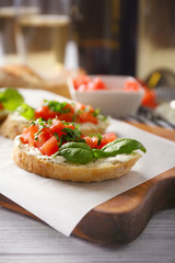 Delicious bruschetta with chopped tomatoes and basil on parchment, closeup