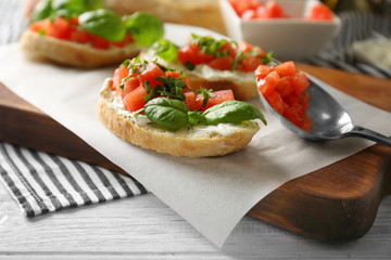 Delicious bruschetta with chopped tomatoes and basil on parchment, closeup