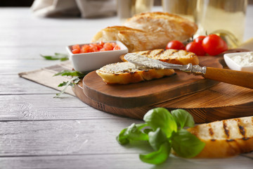 Tasty bruschetta with creamy cheese on wooden board