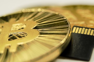 Makro detail of shiny gold Bitcoin coin and microSD memory card