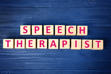 Cubes with text SPEECH THERAPIST on blue wooden background
