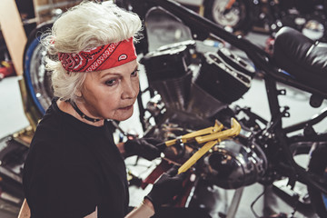 Fototapeta na wymiar Calm pensioner reconditioning bike in garage