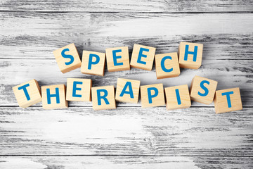 Cubes with text SPEECH THERAPIST on wooden background