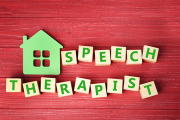 Cubes with text SPEECH THERAPIST on red wooden background