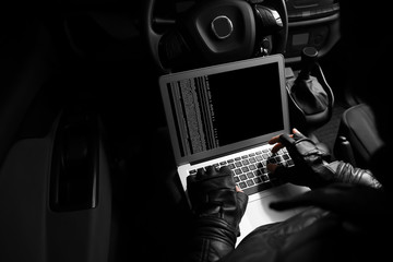 Thief hacking car security system with laptop
