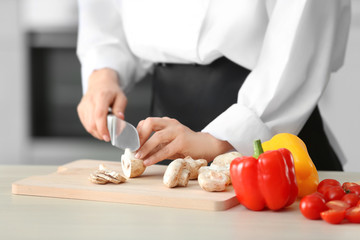 Female chef cutting mushrooms on wooden board closeup