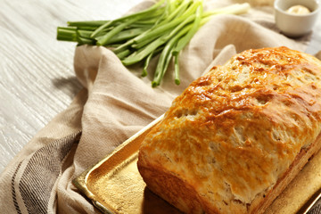 Copper tray with tasty loaf of beer bread on wooden table