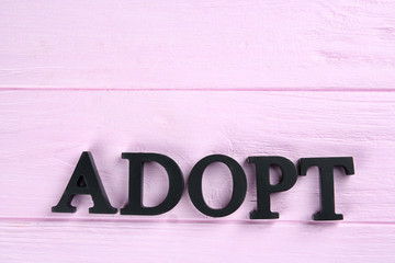 Word ADOPT made of letters on wooden background. Child custody concept