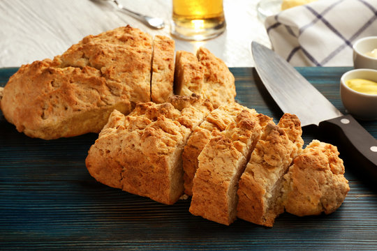 Board with tasty loaf of beer bread on wooden table