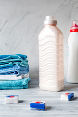 Pile of towels with detergent on laundry background
