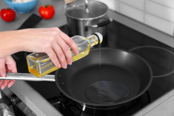 Closeup of woman pouring oil on frying pan
