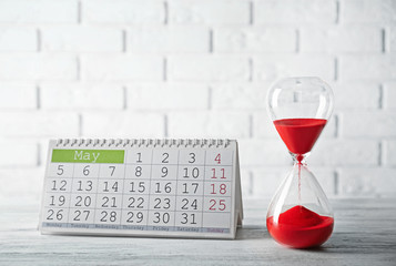 Hourglass with calender on brick wall background