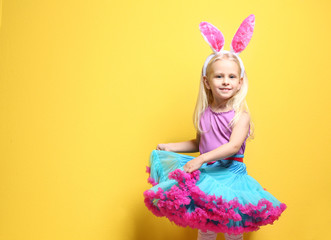 Cute little girl with bunny ears on color background