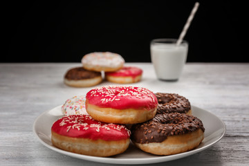 Tasty donuts with cup of milk on table